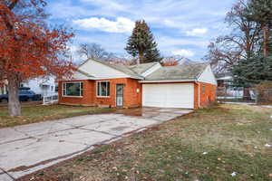 View of front of property featuring concrete driveway, brick siding, and a garage
