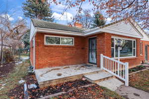 View of front of home featuring a chimney, brick siding, and a gate