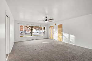 Carpeted spare room with a ceiling fan and baseboards