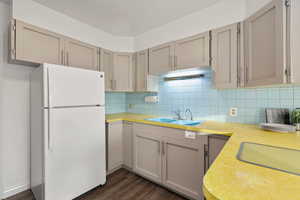 Kitchen featuring freestanding refrigerator, light countertops, tasteful backsplash, and dark wood-style floors