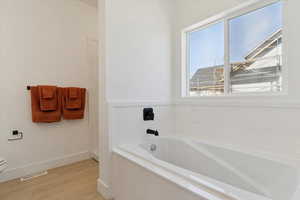 Full bath with a garden tub and light wood-style floors