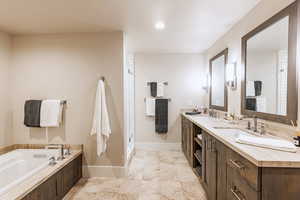 Bathroom featuring double vanity, a garden tub, a shower stall, and recessed lighting