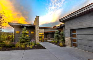 View of front of property featuring stone siding, a chimney, and a garage