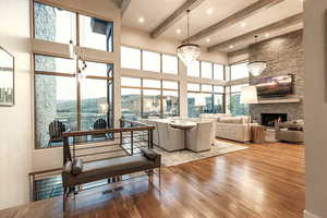 Living area featuring a fireplace, a high ceiling, wood-type flooring, a chandelier, and beam ceiling