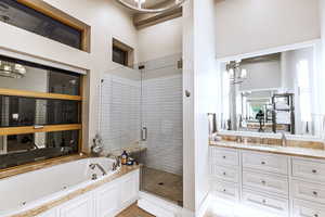 Bathroom featuring a chandelier, a jetted tub, and a shower stall