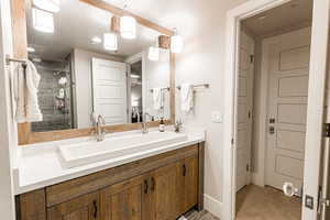 Full bath featuring double vanity and a stall shower