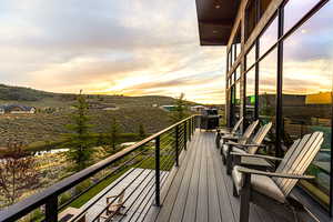 Deck at dusk with a balcony, area for grilling, and a mountain view