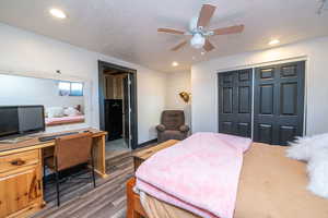 Bedroom with a closet, a desk, dark wood-type flooring, recessed lighting, and a ceiling fan