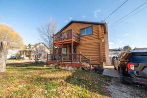 View of front of home with log siding, a deck, and a front yard
