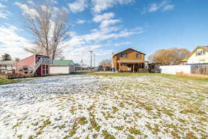 Snow covered back of property featuring stairway, an outbuilding, and a deck