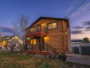 View of front of house with log exterior, a gate, and a balcony