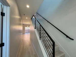 Staircase with wood finished floors and recessed lighting