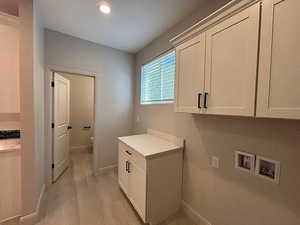 Washroom featuring washer hookup, cabinet space, light wood-style flooring, and recessed lighting