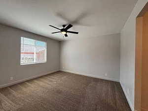 Carpeted spare room featuring a ceiling fan and baseboards