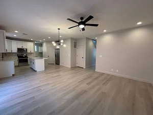 Kitchen featuring open floor plan, white cabinetry, a chandelier, light countertops, and a kitchen island
