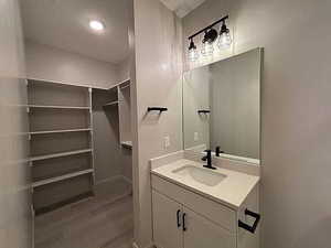 Bathroom with vanity, a walk in closet, and wood finished floors