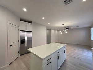 Kitchen with white cabinets, recessed lighting, a center island, stainless steel built in fridge, and decorative light fixtures