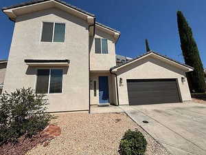 View of front of home with stucco siding, concrete driveway, and a garage