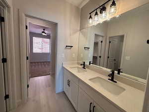 Full bath with double vanity and light wood finished floors