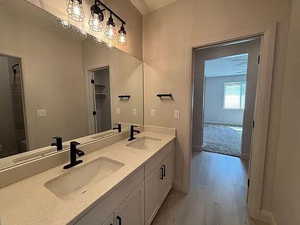 Bathroom with double vanity, a shower with curtain, and light wood-type flooring