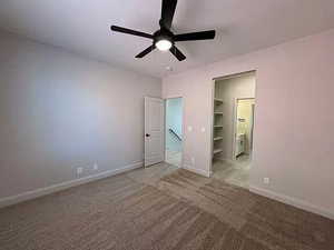 Unfurnished bedroom with ceiling fan, carpet, and connected bathroom