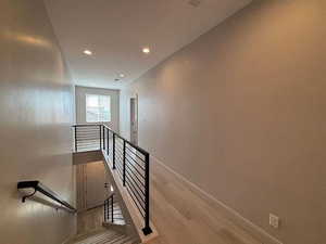 Staircase featuring wood finished floors and recessed lighting
