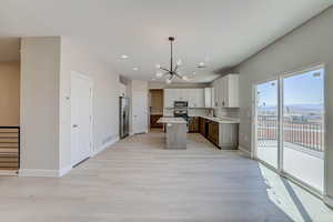 Kitchen featuring light countertops, a chandelier, stainless steel appliances, a kitchen island, and decorative light fixtures