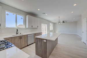 Kitchen featuring light wood-type flooring, light stone counters, a center island, stainless steel appliances, and recessed lighting