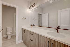Full bathroom with double vanity and light wood-style flooring