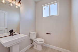 Half bath featuring a chandelier and light wood finished floors