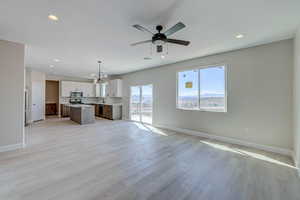 Unfurnished living room with light wood-type flooring, recessed lighting, a chandelier, and ceiling fan