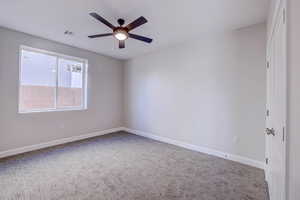 Carpeted empty room with baseboards and a ceiling fan