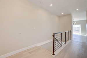 Stairs with recessed lighting, wood finished floors, and a chandelier