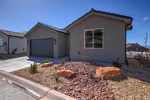 View of front of house featuring concrete driveway, an attached garage, a tile roof, and stucco siding