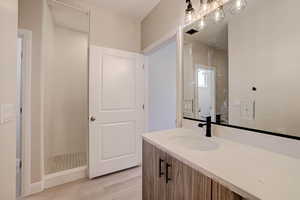 Bathroom with vanity, light wood finished floors, and a chandelier