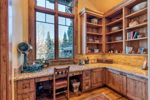 Home office with built in desk, lofted ceiling, and light wood-style flooring
