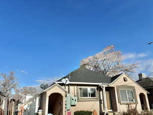 View of front of house with stucco siding and roof with shingles