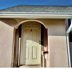 Doorway to property with a shingled roof and stucco siding