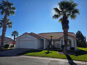 Mediterranean / spanish-style home featuring concrete driveway, an attached garage, a front lawn, and a tiled roof