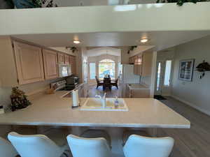 Kitchen with New LVP floors, light countertops, a kitchen bar, and light brown cabinetry.