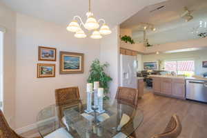 Dining room featuring light wood finished floors, a towering ceiling, and a chandelier