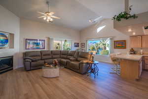 Living room with NEW light  LVP flooring, a glass covered fireplace, a ceiling fan, and high vaulted ceiling, VIEWS OF POND FROM WINDOW