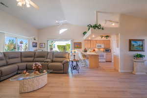 Living room with light wood-type flooring, a ceiling fan, and high vaulted ceiling