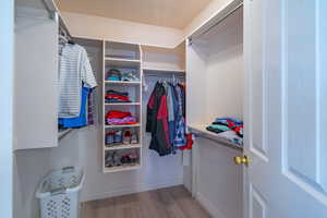 Walk in primary closet with light wood-style LVP flooring