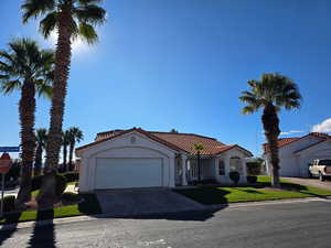 Mediterranean / spanish-style house with concrete driveway, a garage, a tiled roof, stucco siding, and a front yard.