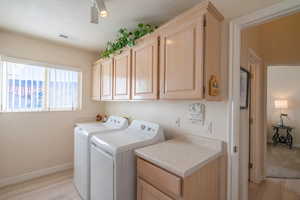 Laundry area featuring cabinet space, washing machine and clothes dryer, and light wood-style floors