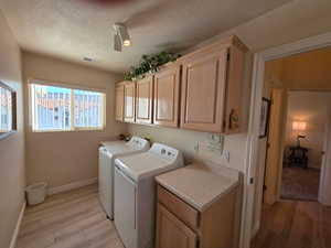 Washroom featuring cabinet space, light wood cabinets, and washer and dryer and small folding table