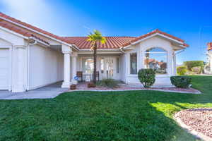 View of front of property with a front lawn, stucco siding, and a tile roof