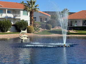 View of home in middle of frame from pond area featuring dolphin statue and water feature