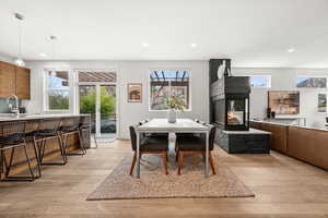 Dining space with light wood-type flooring, recessed lighting, healthy amount of natural light, and a multi sided fireplace